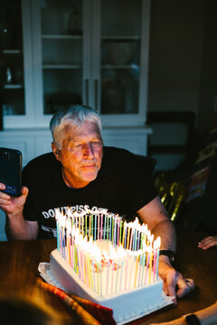 Senior man celebrates birthday with a cake full of lit candles
