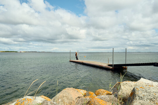 Woman standing alone on a wooden pier by the sea