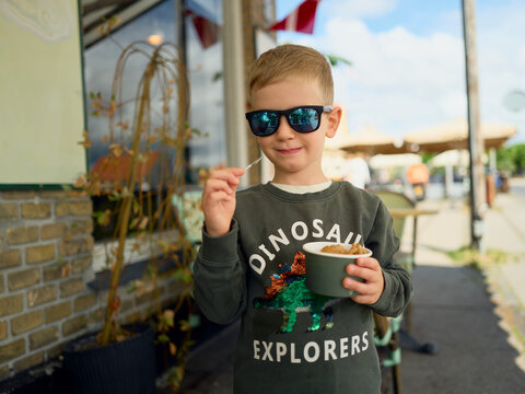 Cool kid with sunglasses eating ice cream outdoors