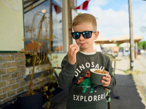 Young boy in sunglasses eating ice cream outside