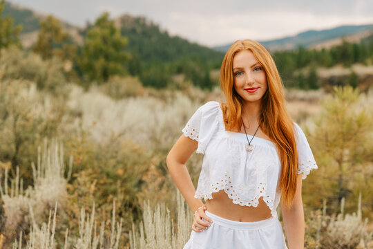 Confident young woman with long red hair posing outdoors