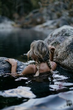 Blonde woman with braids swimming in a serene lake