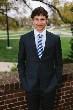 Young man in a suit smiles confidently outdoors