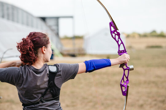 Young woman practicing archery with a purple bow