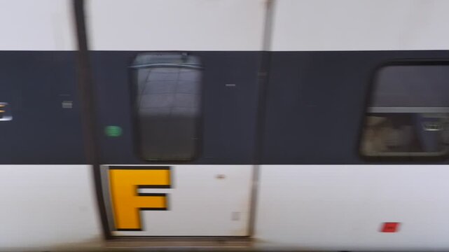 a horizontal stock video footage capturing a moving ETS train showing coach letters, windows, LED display board, and railway track ballast from above.