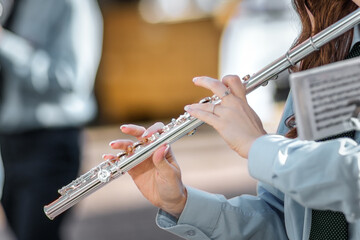 Close-up of a Woman Playing Silver Flute with Sheet Music Outdoors © michelangeloop