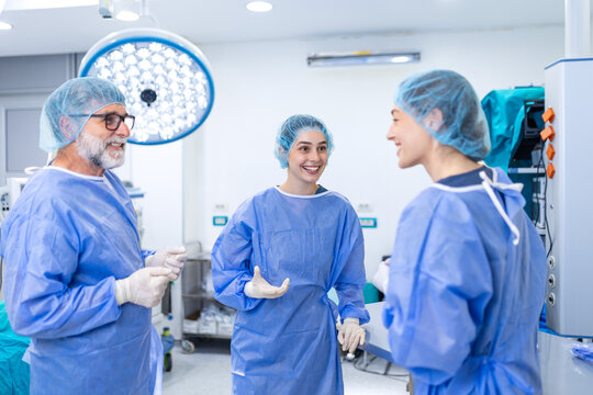 Surgeons talking in hospital operating room. Medical team wearing scrubs and masks discussing procedure, Healthcare and medicine concept, Professional doctors communicating during break in clinic.