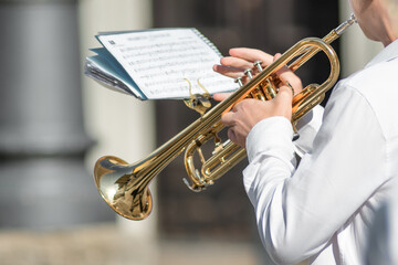 Musician Playing Trumpet Outdoors with Sheet Music in Hand © michelangeloop