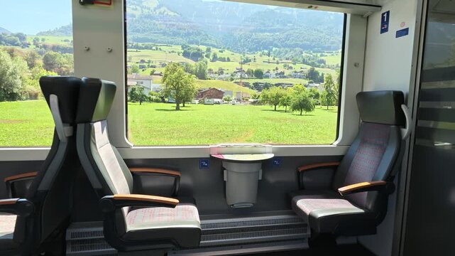 Traveling First Class on the SBB Swiss Train (Brunig Line) from Lucerne to Interlaken. Scenic views of a quiet agricultural town called Giswil seen from the passenger windows of a moving train.