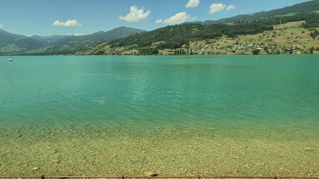 Beautiful views of Lake Sarnen also referred to as the "green lily lake" from the Swiss Railway (Brunig Line) Lucerne to Interlaken. 4K passenger POV looking out the scenic glass window.