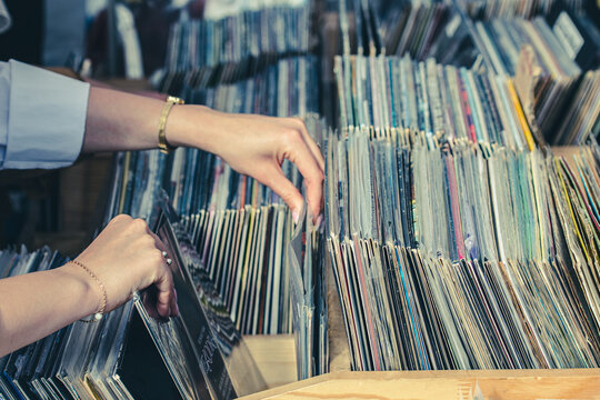 Girl browsing vinyl records in crates at a flea market. Close-up of hands flipping through vintage LP albums