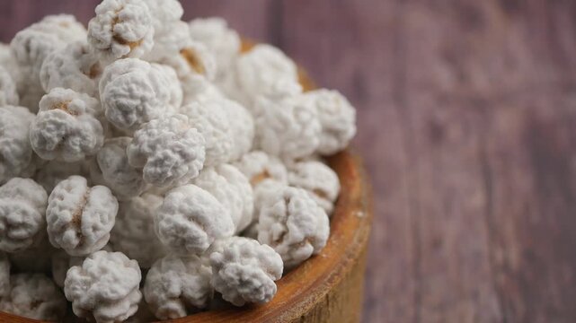 Close up view of roasted chickpeas coated in white sugar in wooden bowl.