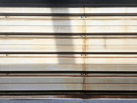 Weathered corrugated metal train wall paneling with rust and industrial texture.