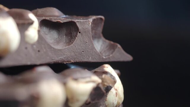 Close up of stacked chocolate pieces with hazelnuts slow motion food preparation cinematic.
