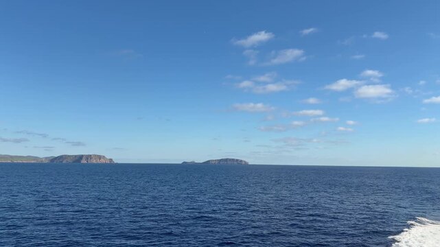 Distant rocky islands in the middle of a deep blue sea under a clear sunny sky scenic view