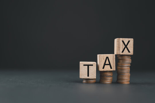 Word tax on wooden block on stacked gold coins to complete Individual income tax payments to government state taxes, Data analysis, paperwork, financial research, report, and Calculate tax refund.