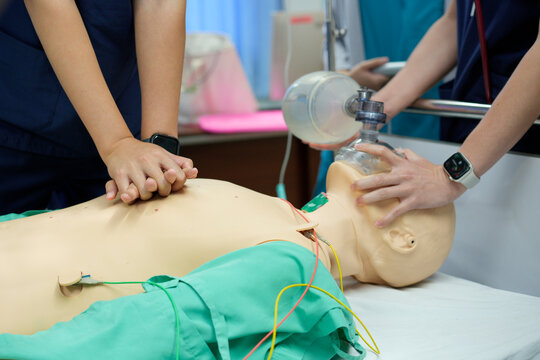 Medical team performing two-person CPR with chest compressions and bag-valve-mask (BVM) ventilation on a simulation mannequin. 