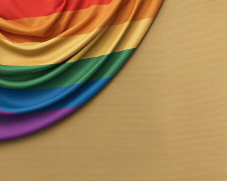 Close-up of a draped rainbow pride flag with vivid stripes on a textured gold backdrop.