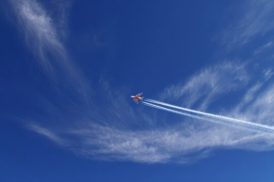 An acrobatic jet fighter soars through a clear blue sky, leaving a contrail as it performs an aerial maneuver amidst wispy cirrus clouds. ..Created with Generative AI, not depicting real subjects.