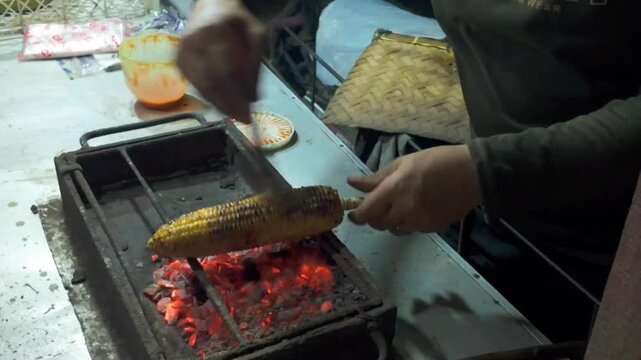Golden corn is slowly roasted over glowing charcoal, as the heat caramelizes each kernel and creates a warm, smoky street food atmosphere.