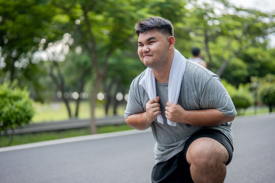 Asian plus-size man taking a break while exercises outdoors in garden.