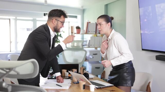 Man and girl colleagues are arguing excitedly in office of company. Disagreements, insubordination, inconsistency of views 