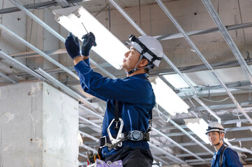 工事現場で配線工事をする作業員の男性 © M