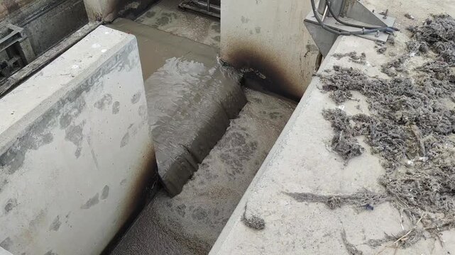 A high-angle close-up view of the influent entrance channel to an aeration basin with thick foam and scum accumulation at a wastewater treatment.