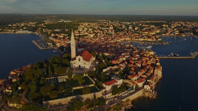 Aerial video of Rovinj, Croatia, showing the historic old town on a rocky peninsula surrounded by the Adriatic Sea at dusk 