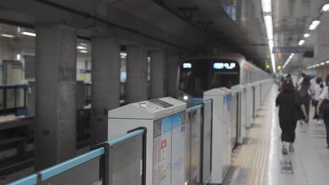 selective focusing to platform gate while some passenger waiting for arriving subway train commuter and train commuter approaching to train platform,japan train public train transportation