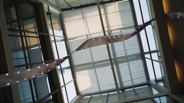 Rotating cam revealing atrium skylight with shades to show twisted lit sculpture and steel frame