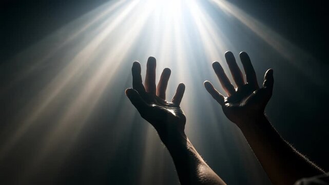 Light shines on outstretched hands reaching toward the sky in a dark space during a moment of reflection. High quality 4k footage
