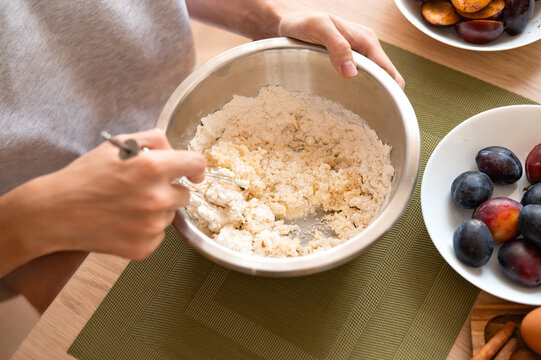 Person mixing dough in bowl, authentic lifestyle home cooking process, soft selective focus, natural light