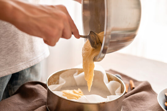 Person spoon a dough into springform pan, soft selective focus, lifestyle home interior, authentic home bakery cooking