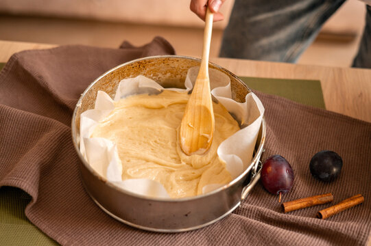 Person placing dough in old springform pan, making homemade plume pie bakery. Soft selective focus, natural light
