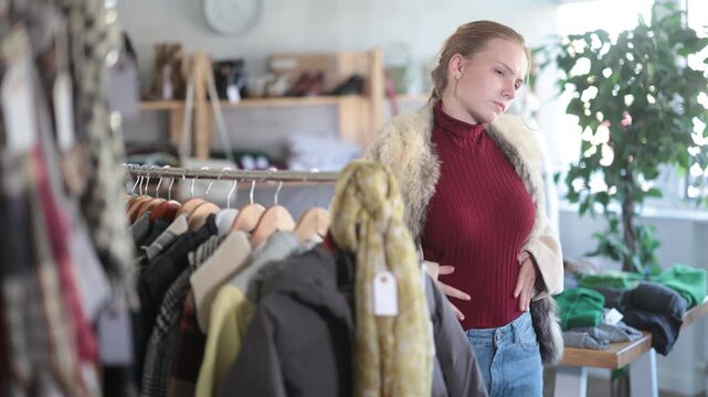 Happy teenage girl posing in warm fur coat during shopping in retail outlet 