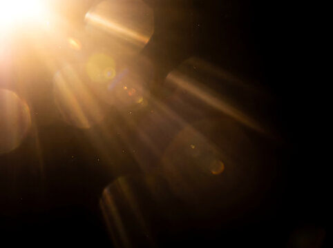 Golden lens flare on black background, warm sun light leak, cinematic optical flare overlay