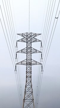 High voltage electrical transmission pylon tower with power lines against a clear sky