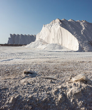 Massive white salt mounds at a salt production site under bright daylight