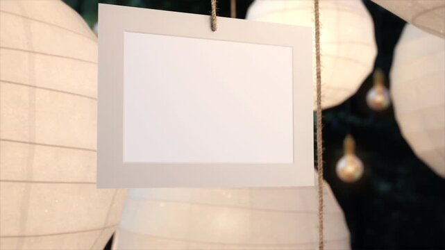 Blank hanging sign frame with soft lighting and decorative paper lanterns.
