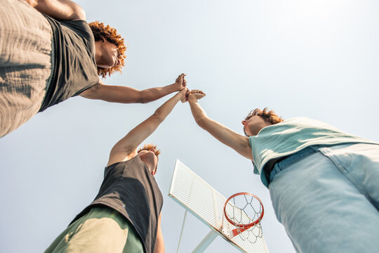 Multicultural friends huddling celebrating teamwork on basketball court