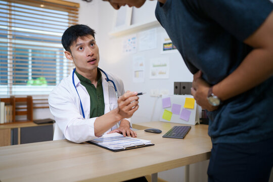 Crohn's disease or ulcerative colitis concept. Doctor counseling male patient with abdominal pain in hospital examination room, ideal for healthcare and medical service