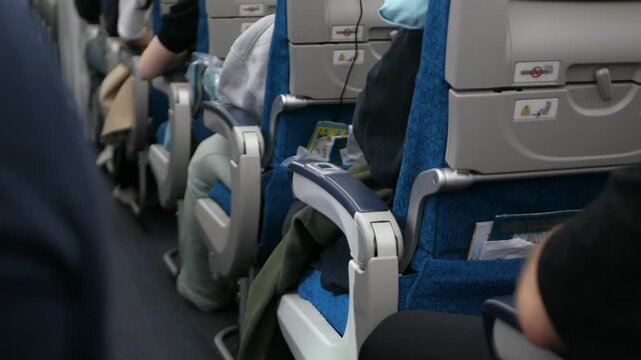 Back of plane corridor aisle with selective focusing on plane seat from the back while aircraft traveling. Passenger seated inside airplane traveling in flight onboard for holiday vacation