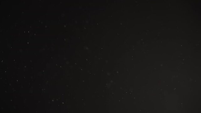 Real dust particles floating mid air over dark background