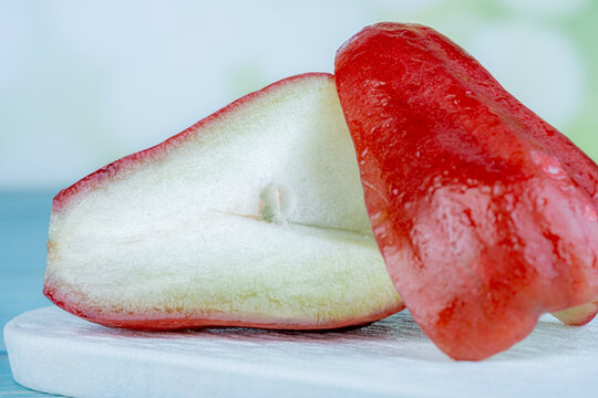 Close-up shot of crisp red wax apple halves with juicy white core.