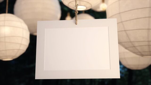 Blank white paper card hanging in front of illuminated paper lanterns.