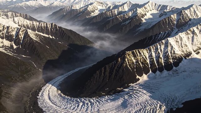 Tracking drone moving forward and down over high alpine cirque, revealing crescent-shaped glacier