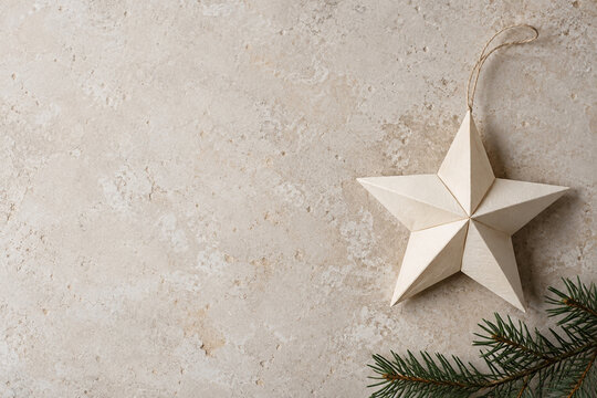 Hand folded paper star ornament on a neutral holiday background