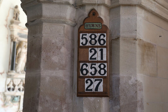A close up view of a vintage wooden board showing the hymn numbers in an ancient chapel in England, U.K.