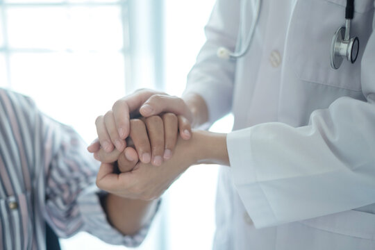 Doctor holding hands of patient to give comfort support and reassurance in hospital clinic for medical healthcare compassion concept